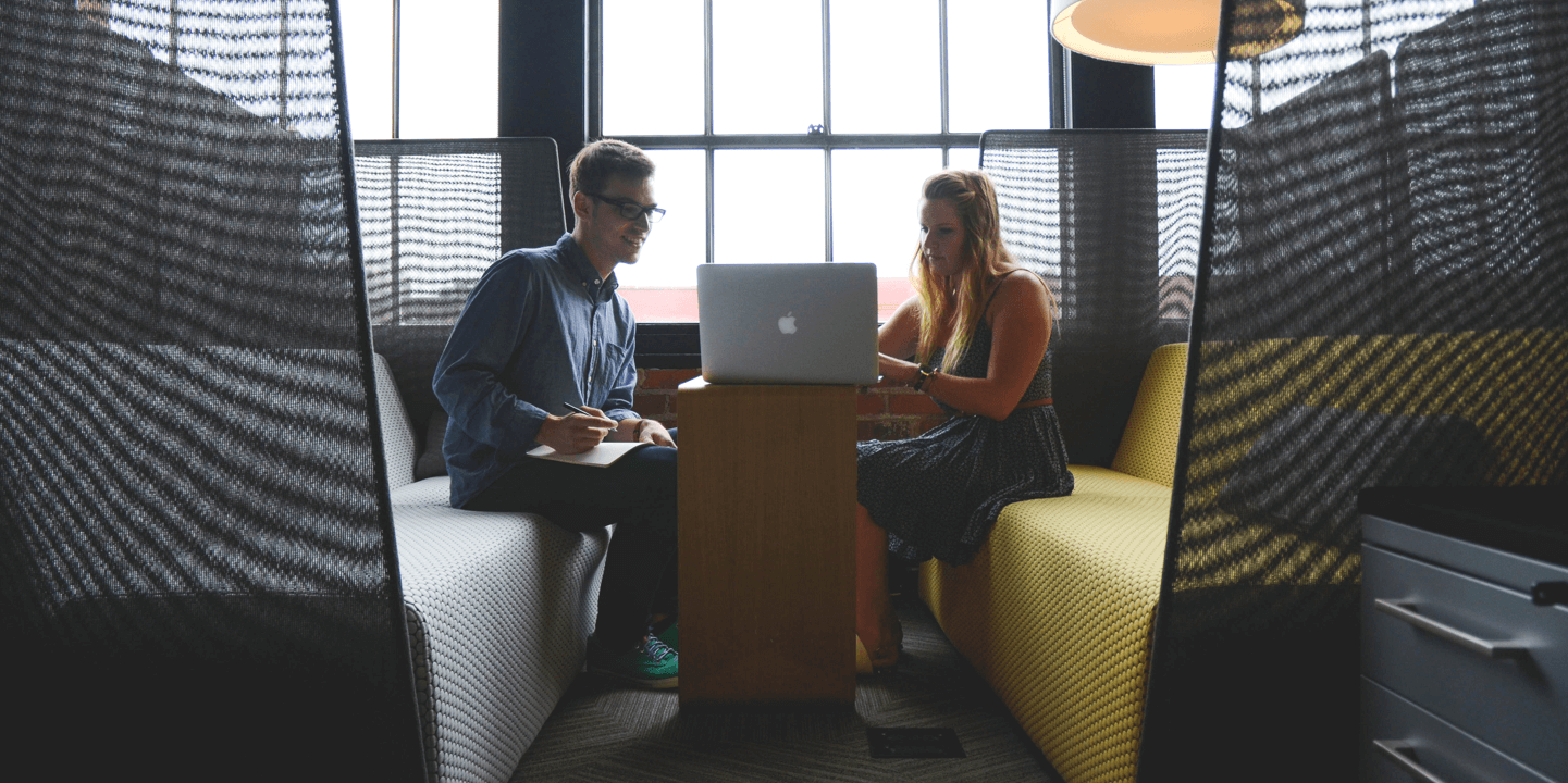 Two young professionals collaborate around a laptop