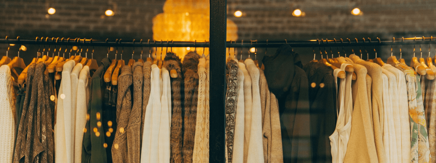 A rack full of clothing inside a brick store