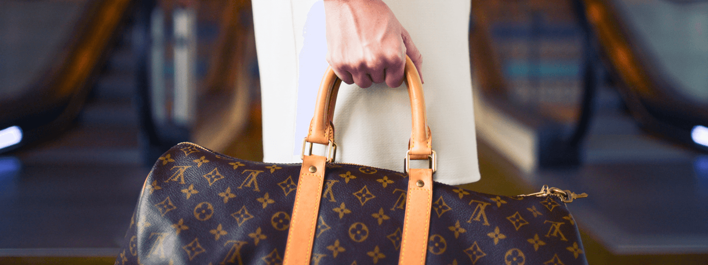 A female in a white dress holding a Louis Vuitton bag