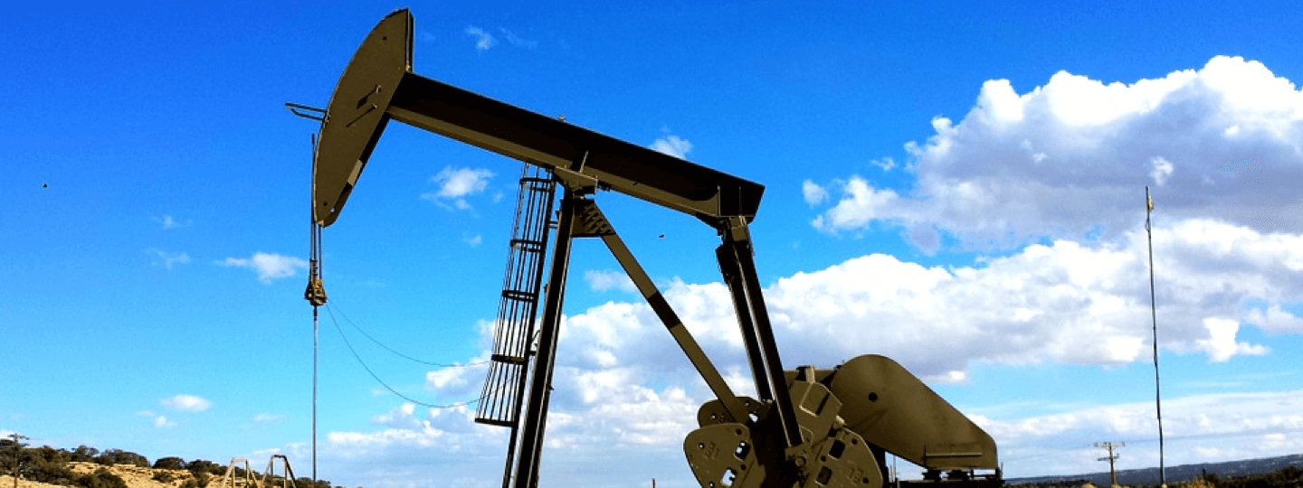 A small oil rig against a partly cloudy blue sky