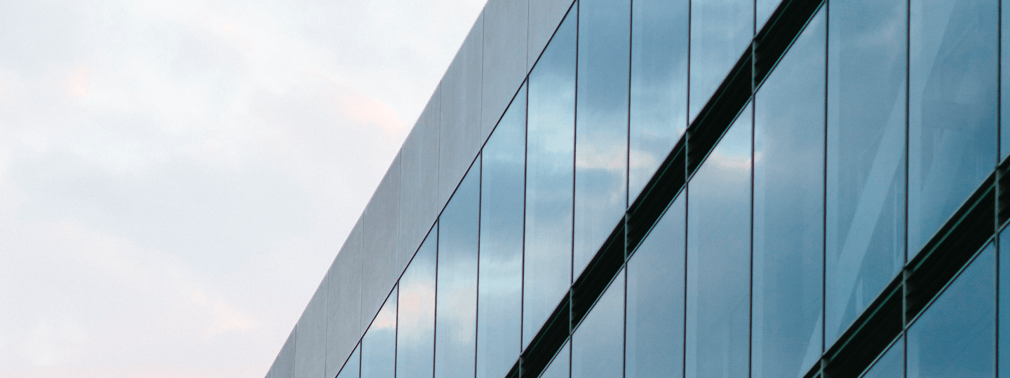 The side of a glass building against a cloudy sky