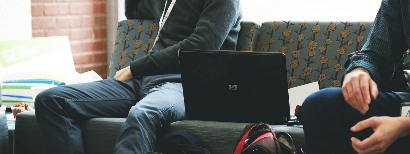 Two people sitting on a couch with a laptop between them