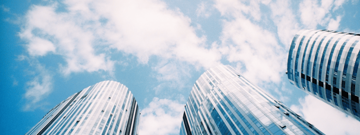 Looking up the sides of three tall, rounded office buildings