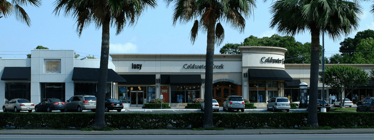 Three palm trees sit in front of an upscale strip mall