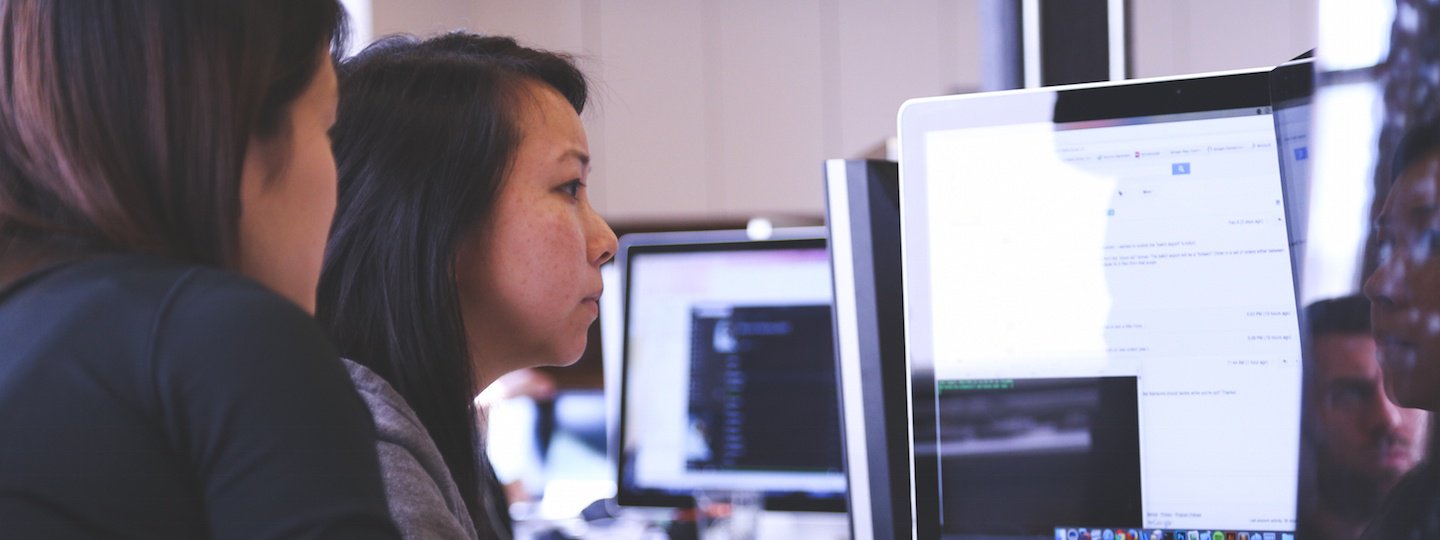 Two females collaborating around a computer