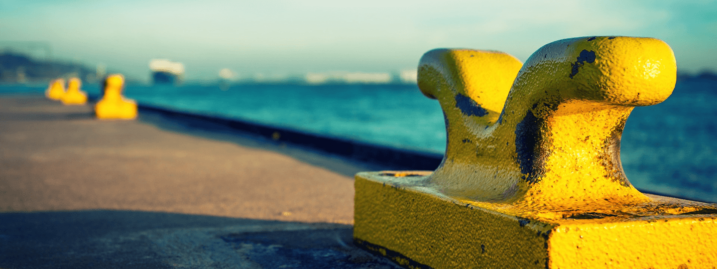 Closeup of large, yellow tie down cleats on a port loading dock