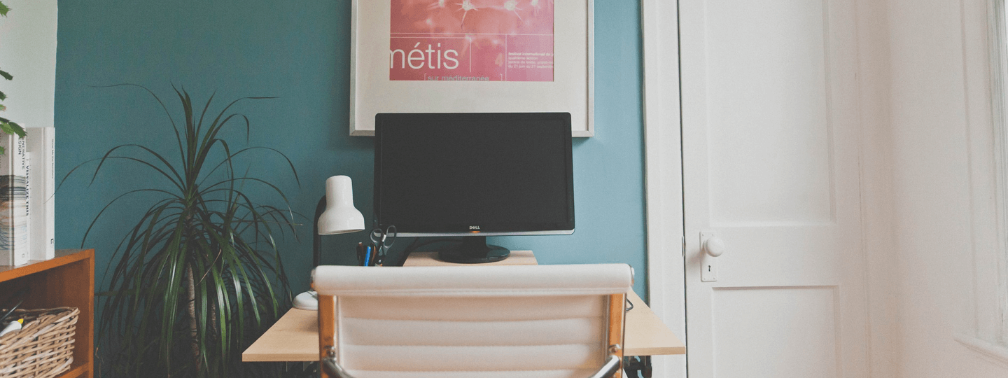 A computer on a small desk within a small room