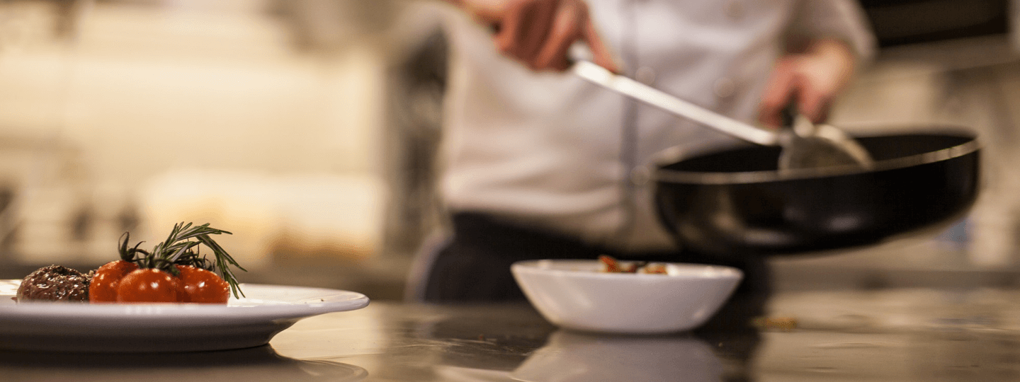 A chef dishing up food in a kitchen