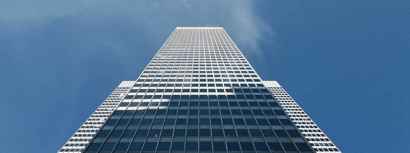 Looking up the side of a tall office building against a blue sky