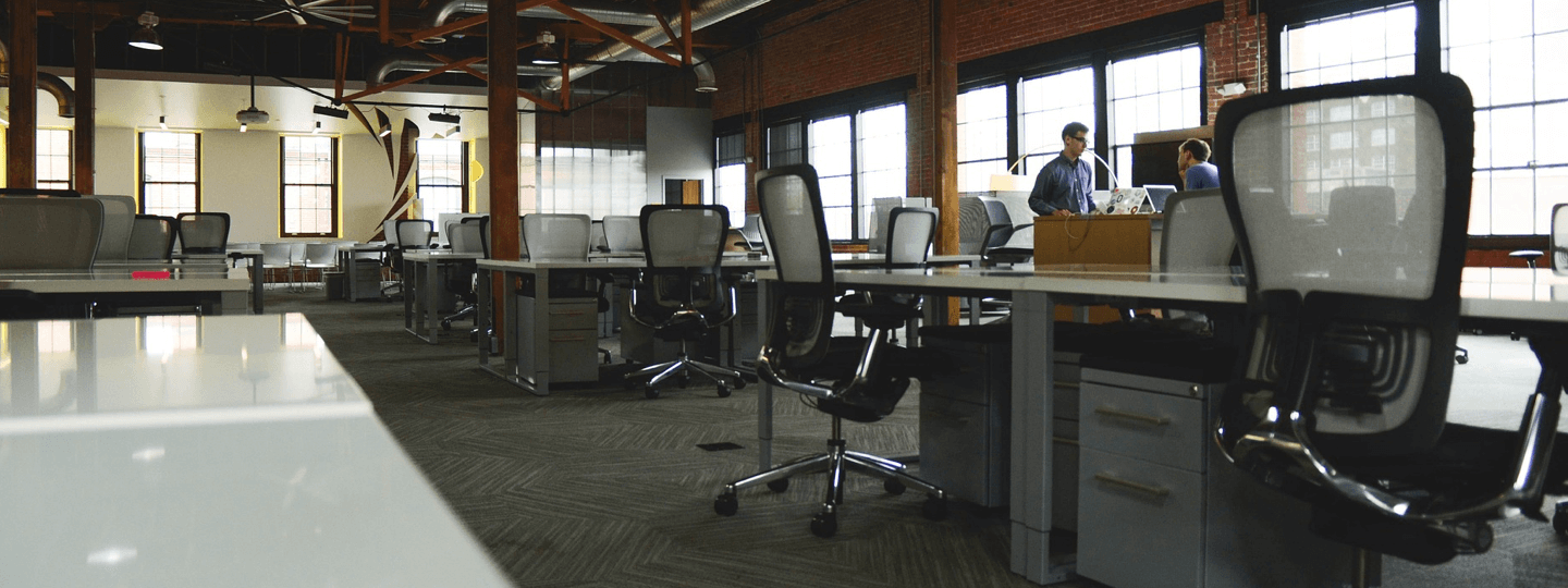 Two males in a large, open, brick office space