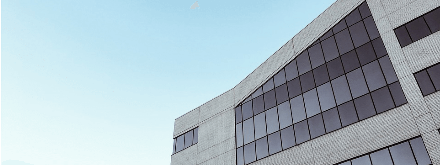 An upper corner of an office building against a blue sky