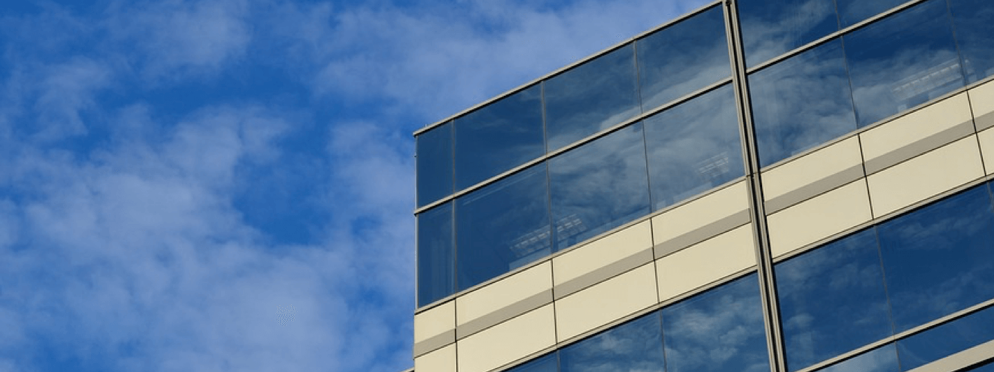 An upper corner of an office building against a blue sky