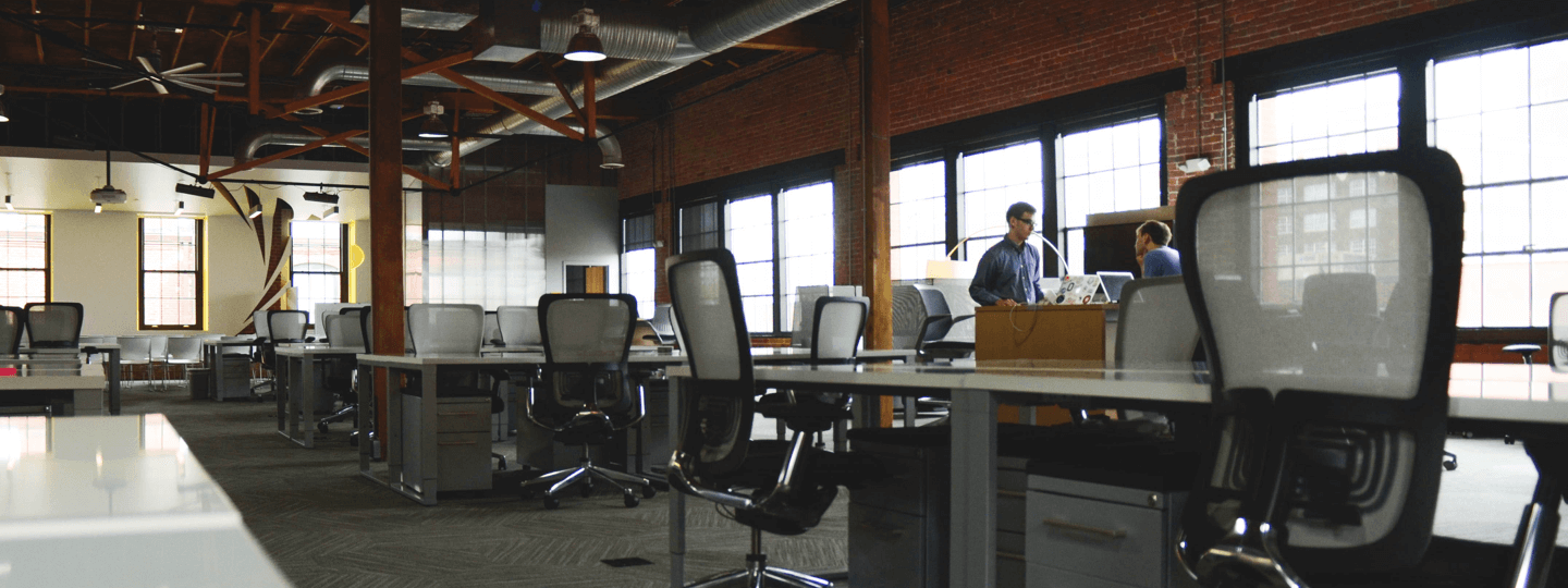 Two males in a large, open, brick office space