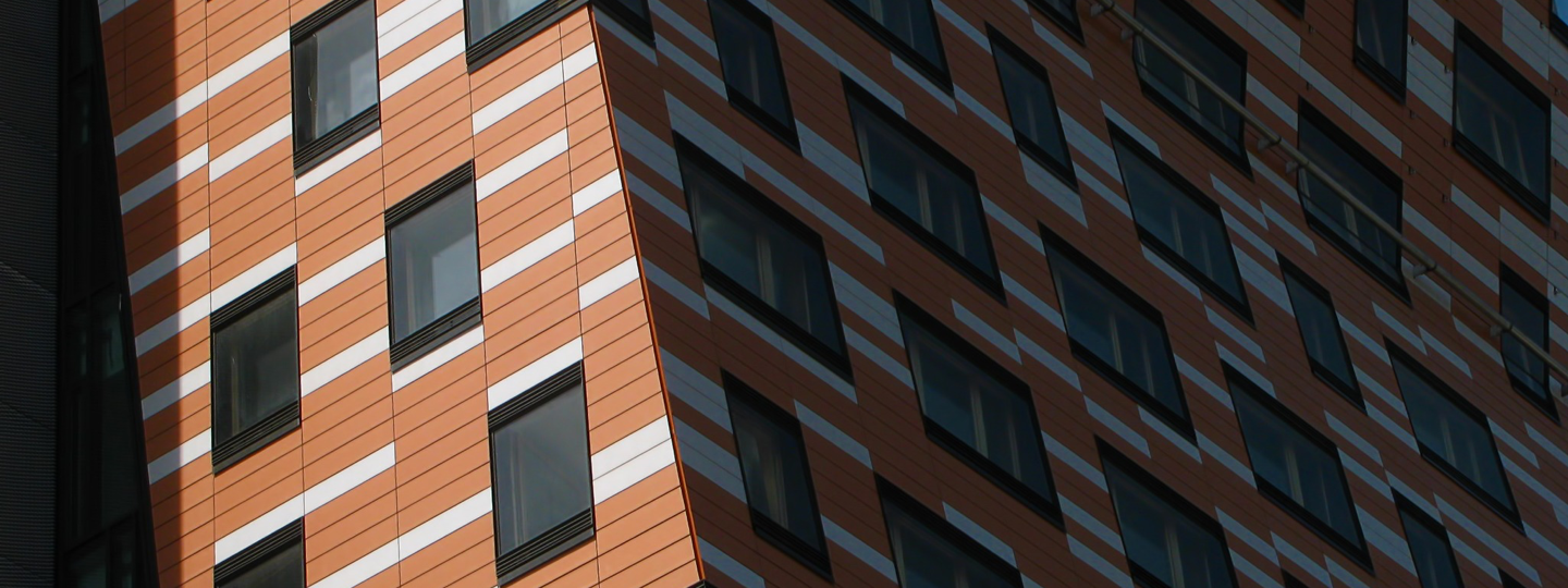 The side of a large, uniquely shaped office building with orange and white siding