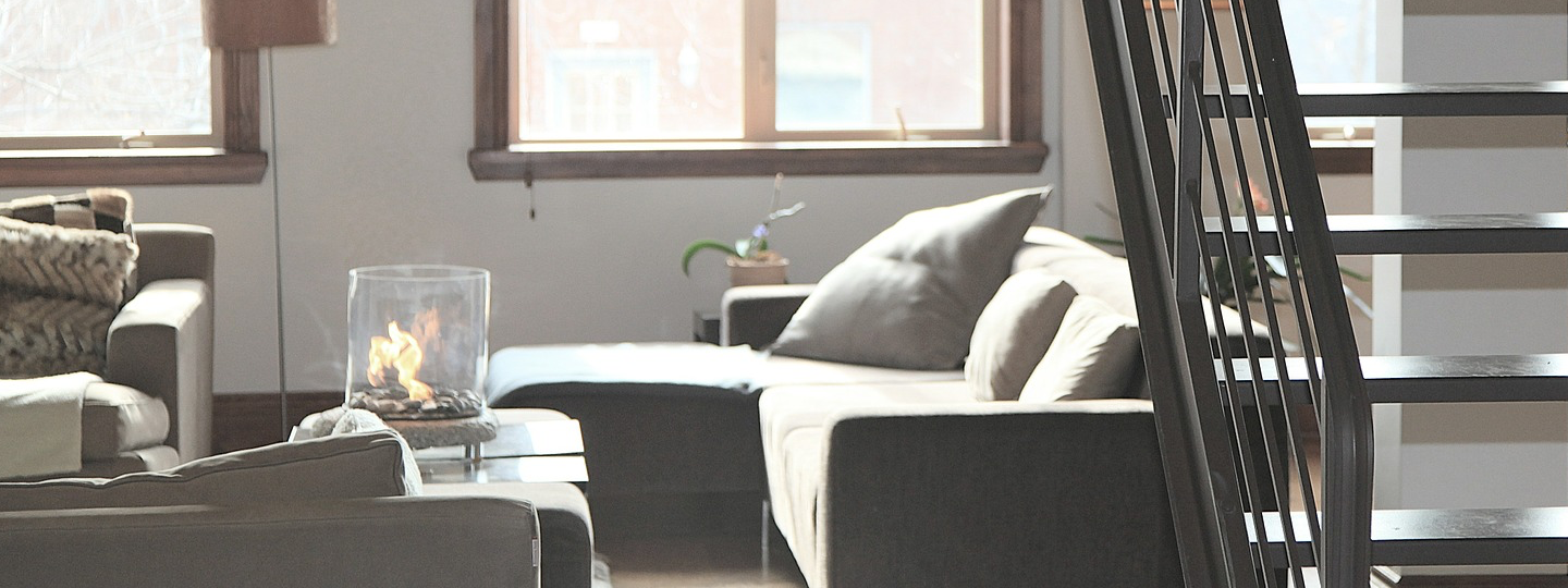 A living room with three couches behind a staircase