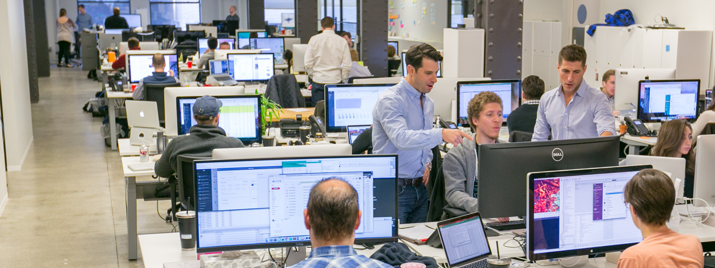 A crowded office space with many computers and employees