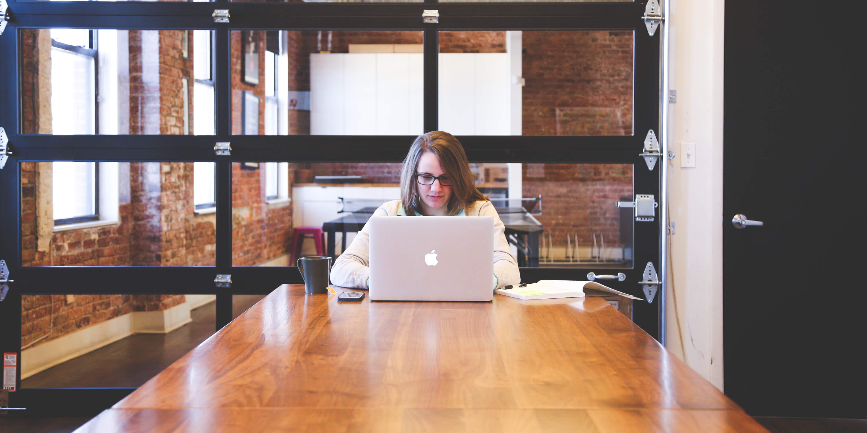 A young female working on a laptop at a wood table