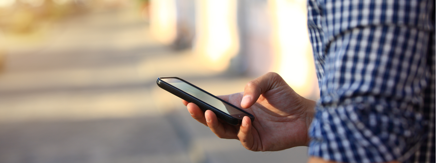 A person in a blue checkered shirt using a cellphone