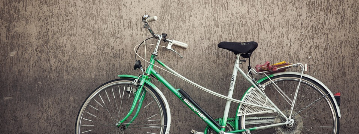 A green Bianchi bike leaning against a wall