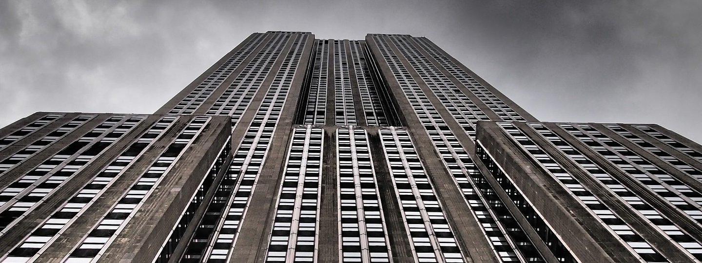 Looking up a large high rise building against a cloudy sky