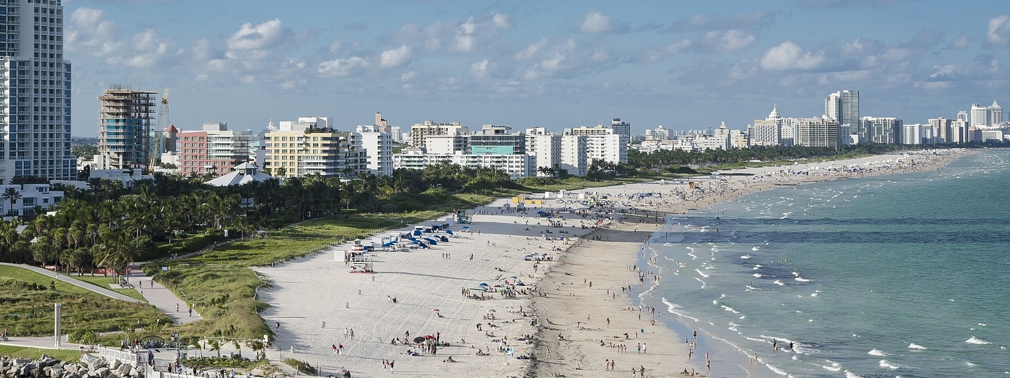 A very large, crowded beach next to a row of highrise buildings