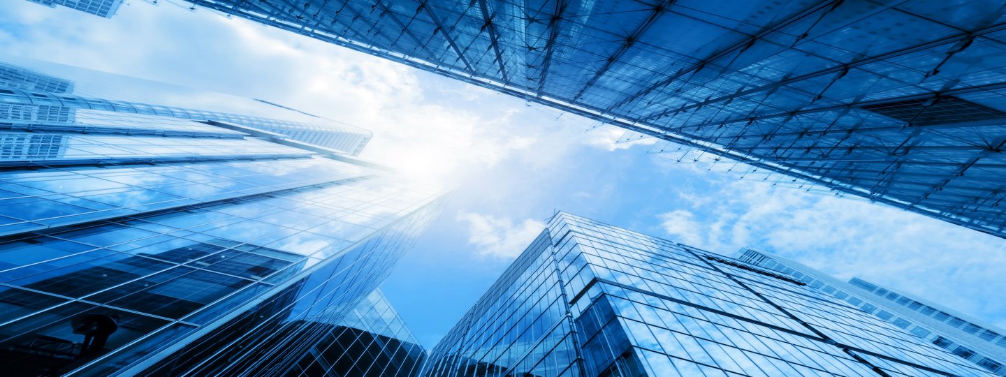 Looking up several large office buildings to a blue sky