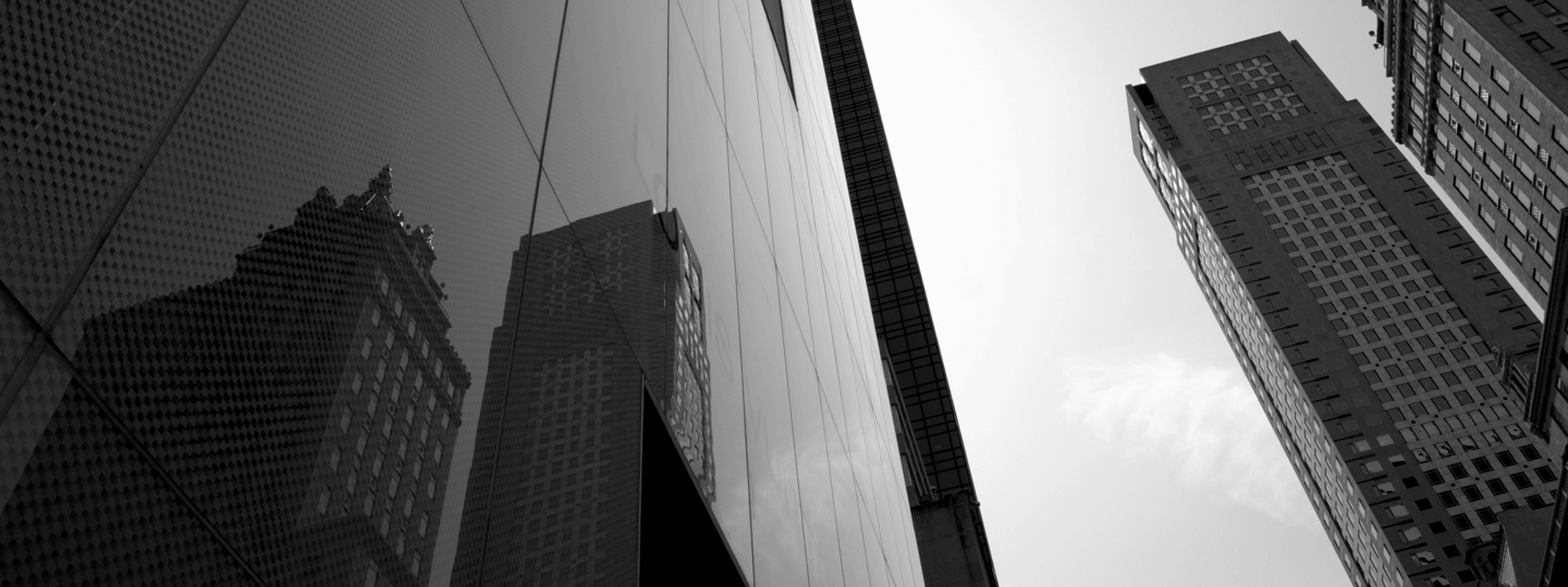 A clean, glass facade of a large high rise next to older high rise buildings