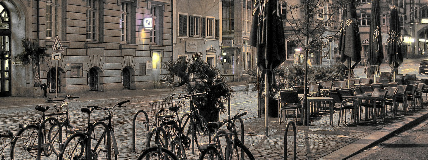 A city street with several parked bikes and resteraunt seating