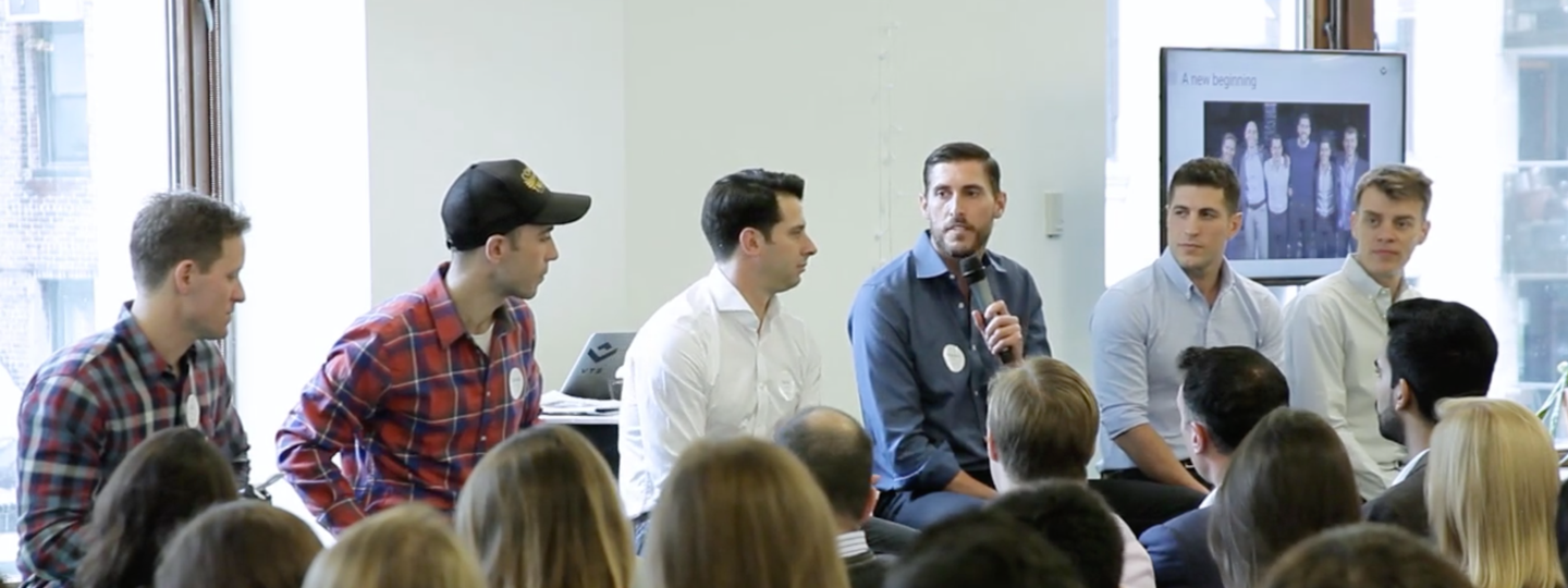 A panel of 6 men speaking at a conference