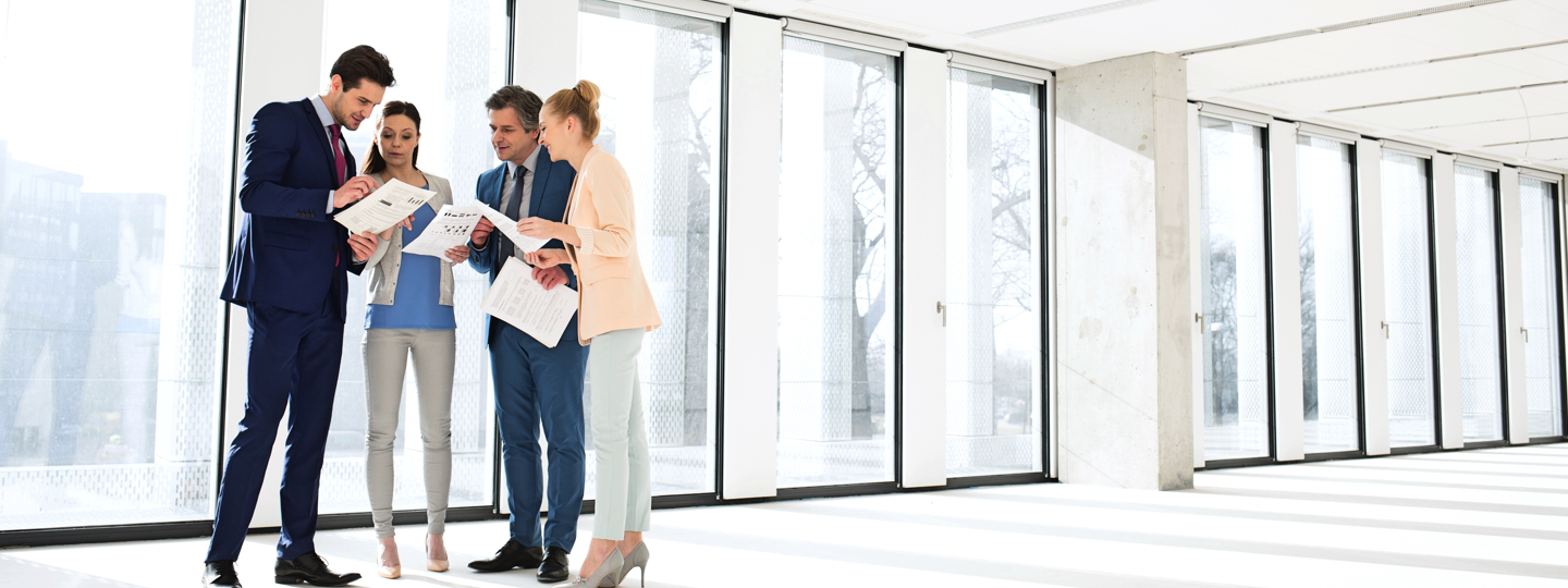 4 professionals discussing papers in an office building