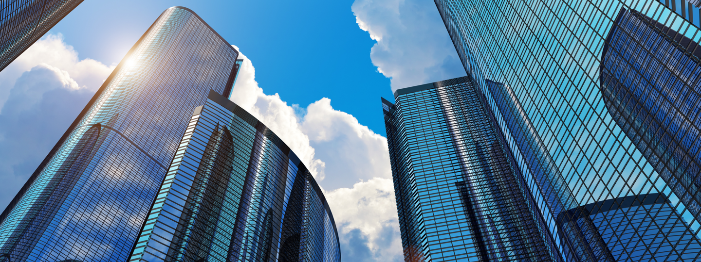 Looking upwards between very tall buildings with blue tinted glass