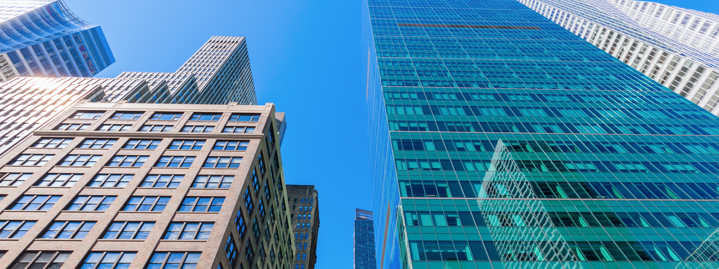 Looking upwards at the facades of several large high rise buildings