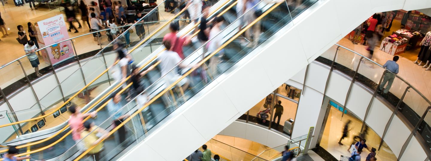 A blurry escalator within a crowded mall