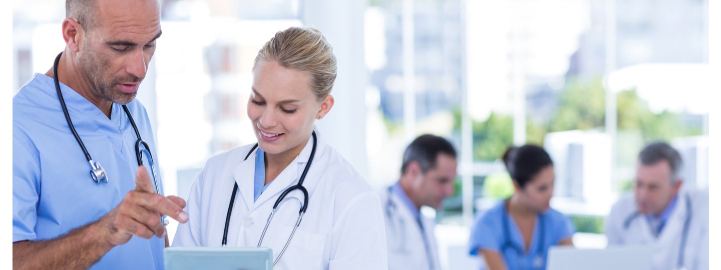 Medical professionals collaborating around a tablet and laptop