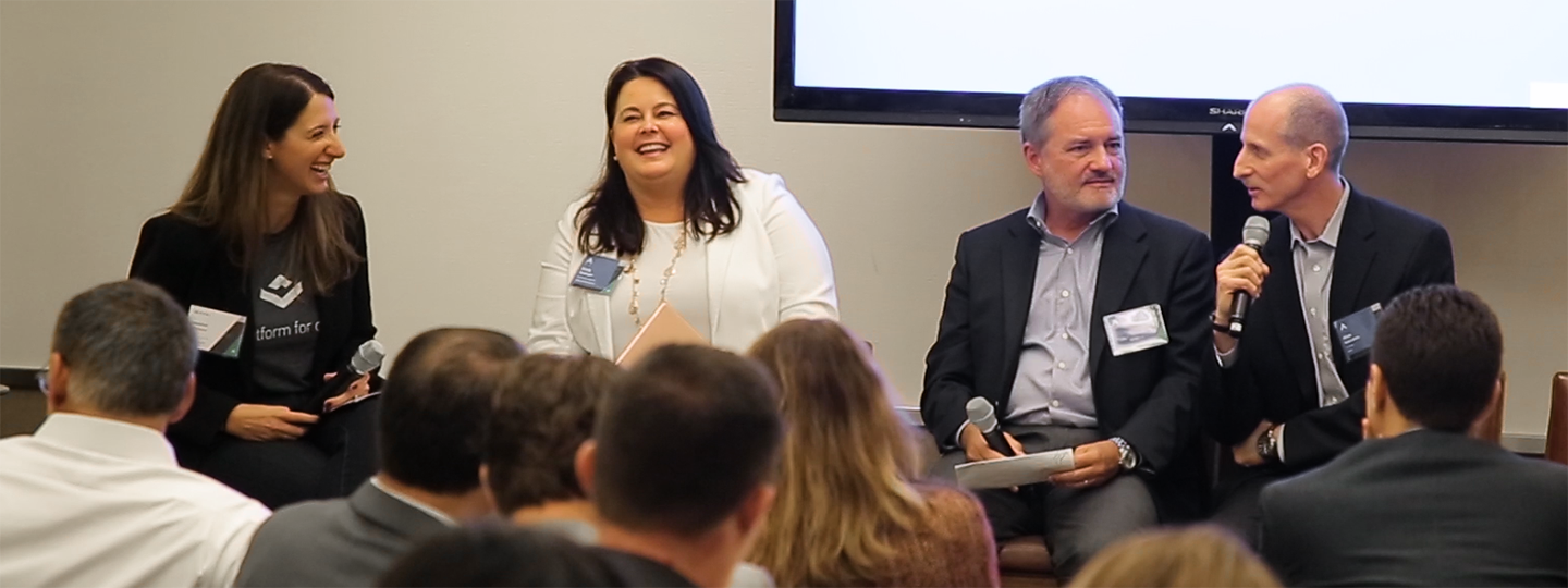 Four panelists speaking in a conference room