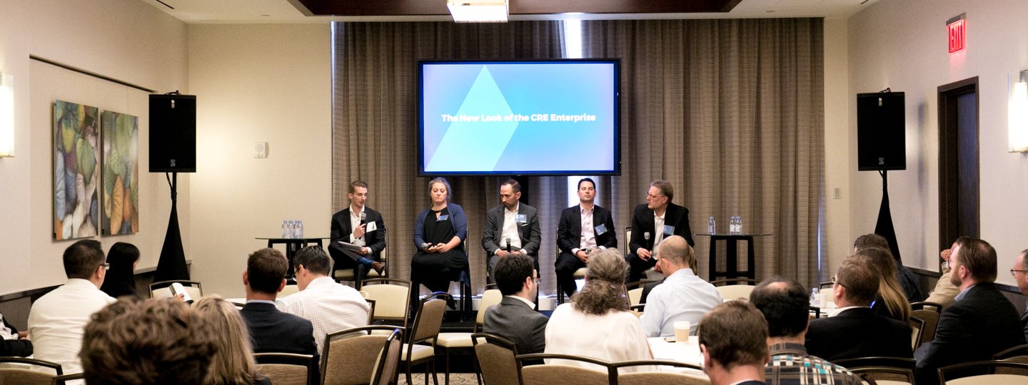 Five panelists in discussion with a full conference room