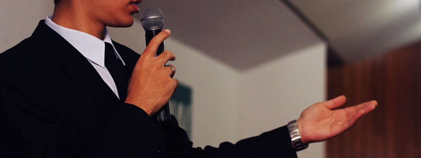 A man in a suit talking into a microphone