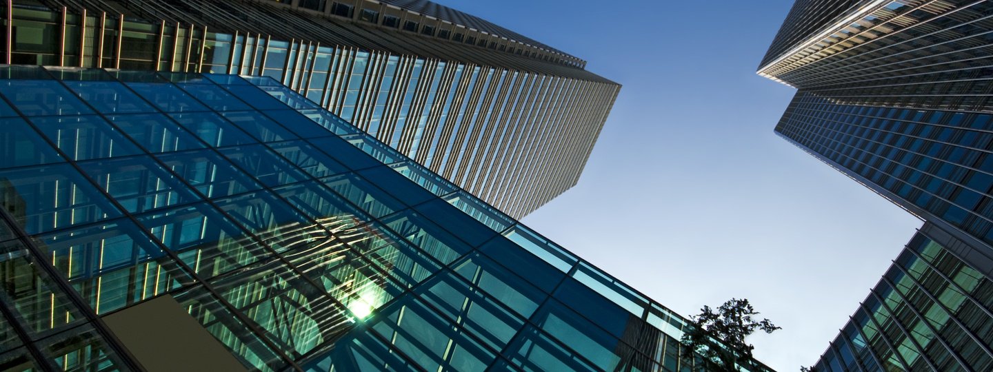 Looking up the side of several large office buildings to a blue sky