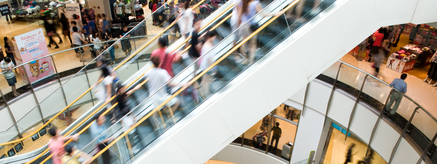 A blurry escalator within a crowded mall