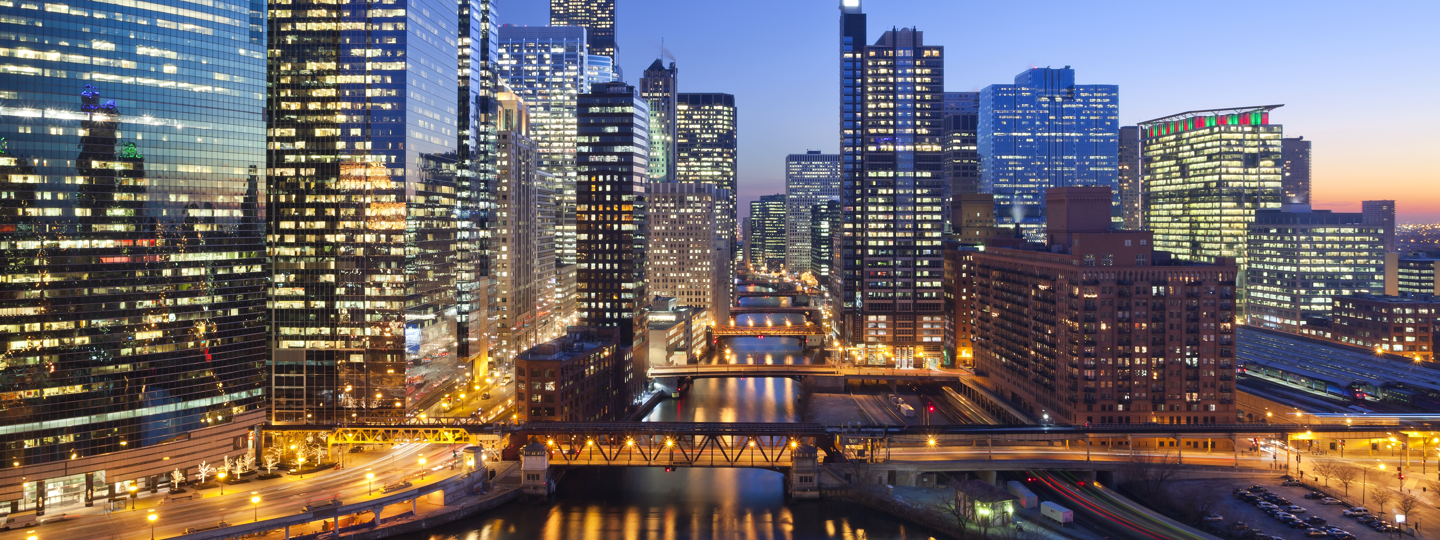 A waterway with several bridges splits a large city at dusk