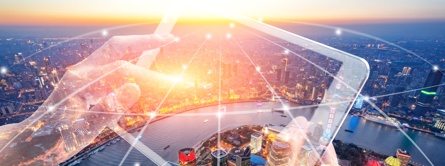 An aerial view of Shanghai overlaid by hands working on a tablet