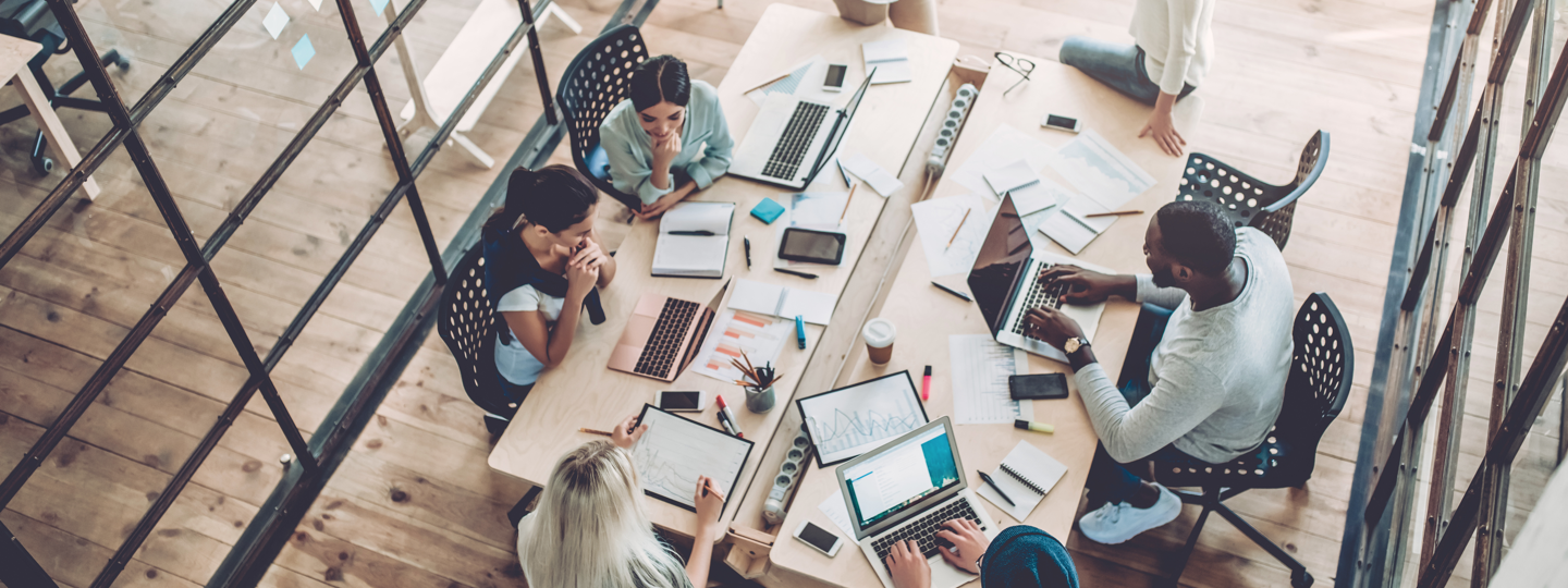 Top down view of seven employees collaborating around a table